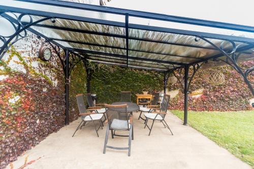 a pergola with chairs and a table in front of a wall at Budyně Apartment in Budyně nad Ohří
