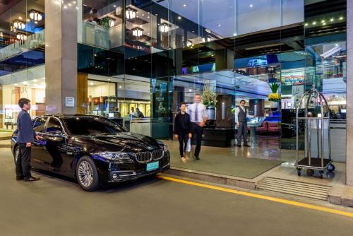 a group of people standing around a car in front of a building at Novotel Bangkok on Siam Square in Bangkok