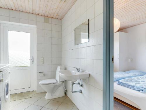 a bathroom with a toilet and a sink and a bed at Four-Bedroom Holiday home in Tarm 3 in Hemmet