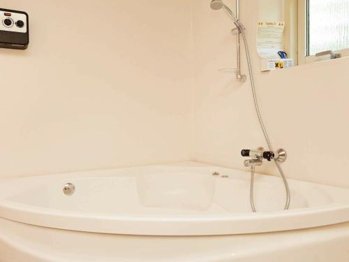 a white bath tub with a shower in a bathroom at 12 person holiday home in H jslev in Bøstrup