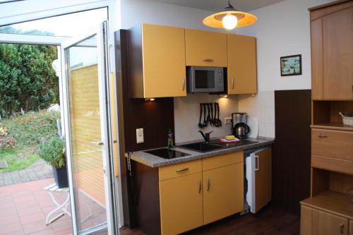 una cocina con armarios amarillos y una puerta corredera de cristal en Fewo Kasch, en Binz