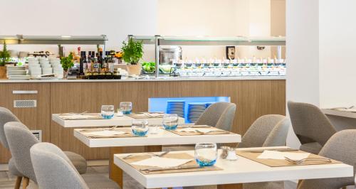 a restaurant with white tables and chairs and a counter at Globales Don Pedro - Adults Only in Cala de Sant Vicent
