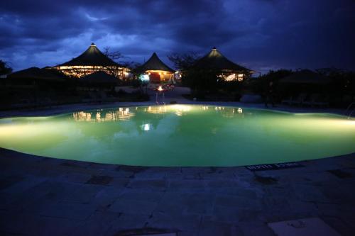 a pool of water at night with buildings in the background at AA Lodge Maasai Mara in Talek