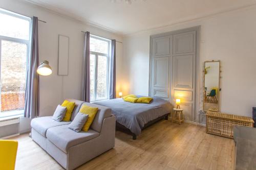 een slaapkamer met een bed, een bank en een spiegel bij Les Augustins in Amiens