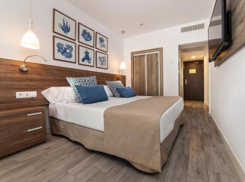 a bedroom with a large bed with blue pillows at Globales Don Pedro - Adults Only in Cala de Sant Vicent