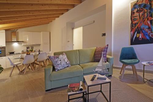 un salon avec un canapé vert et une cuisine dans l'établissement Apartments Villa Bougainville, à San Felice del Benaco