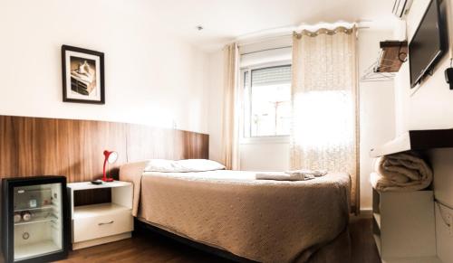 a small bedroom with a bed and a window at Porto Rei Residence Hotel in Rio Grande