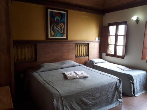 a bedroom with two beds with a towel on them at Pousada Raio de Sol in Jaguarão