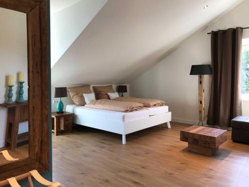 Schlafzimmer mit einem weißen Bett und Holzboden in der Unterkunft Lauras Weinherberge in Leinsweiler