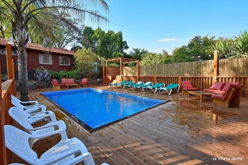 a backyard with a pool and chairs and a fence at אחוזת הוואי in Had Nes