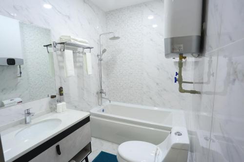 a white bathroom with a toilet and a sink at Hotel 777 in Dushanbe