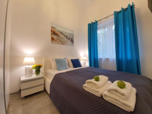 a bedroom with blue curtains and a bed with towels at DWIE SOSNY-Apartament na wydmie - 365PAM in Ustronie Morskie