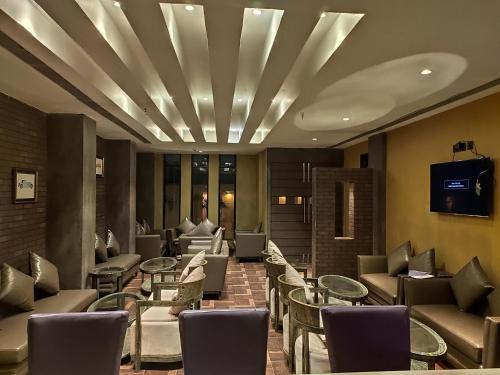 a lobby with tables and chairs and a tv at Pal Heights Mantra in Bhubaneshwar