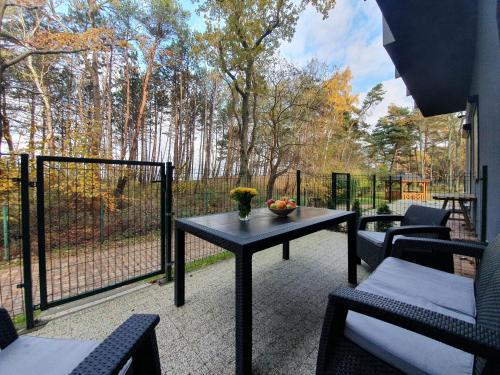 a patio with a table and chairs and a fence at 365PAM - DWIE SOSNY - Apartament na wydmie - SAUNA, JACUZZI, SIŁOWNIA, BAWIALNIA in Ustronie Morskie