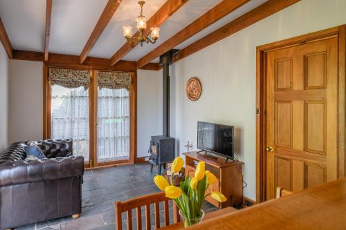 a living room with a couch and a television at BRIDGE COTTAGES Sargeants & Armoury Cottages 1823 - HISTORY & CHARM in Richmond