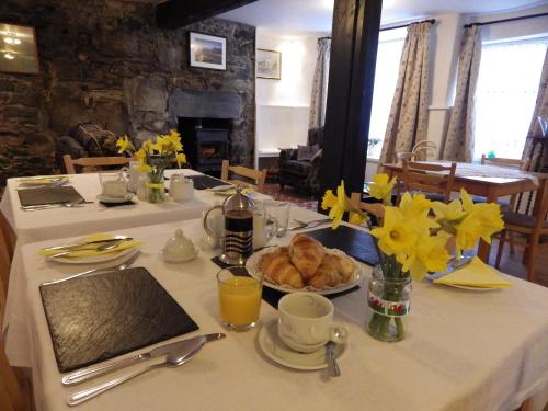 stół z talerzem rogalików i żółtych kwiatów w obiekcie Aber Cottage B&B w mieście Dolgellau