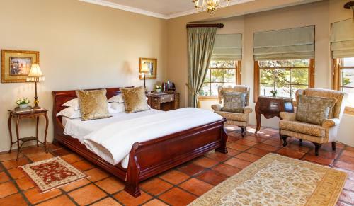 a bedroom with a large bed and two chairs at La Plume Boutique Hotel & Spa in Oudtshoorn