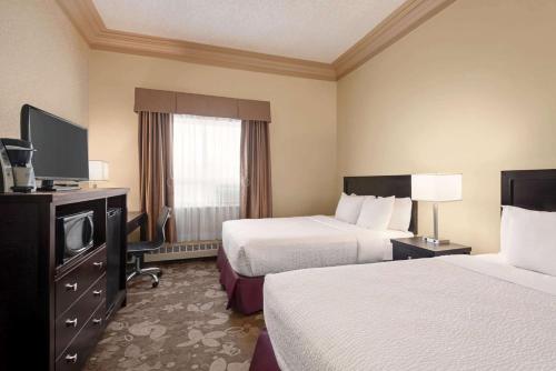 a hotel room with two beds and a television at Nova Inn Yellowknife in Yellowknife