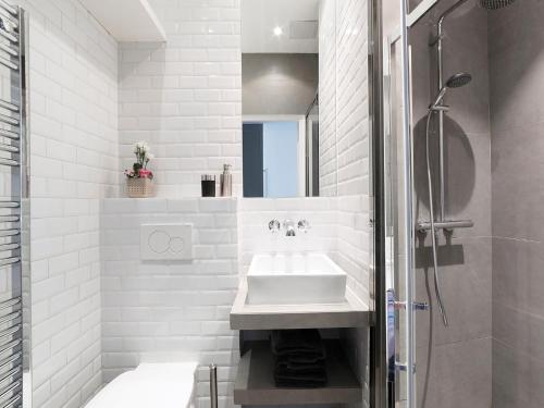 een witte badkamer met een wastafel en een douche bij Studios de Charme à Montmartre in Parijs