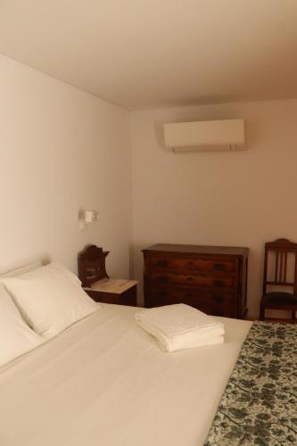 a bedroom with a white bed and a dresser and a window at Casa Gil Vicente in Almada