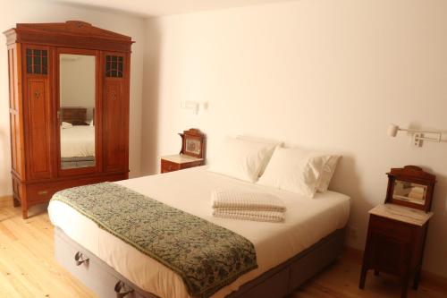 a bedroom with a bed with a dresser and a mirror at Casa Gil Vicente in Almada