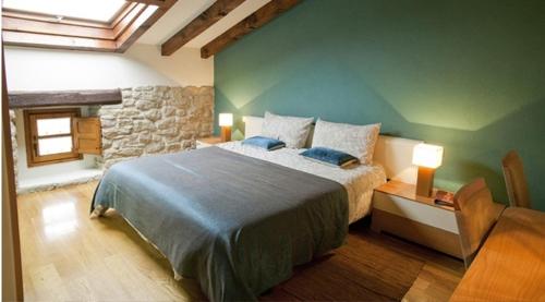 a bedroom with a large bed and a stone wall at Casa Rural Lakoak in Garínoain