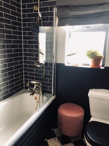 a bathroom with a tub and a toilet and a window at Woodend Cottage in Dumfries