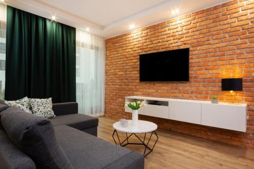 a living room with a brick wall with a tv at Apartments Rzeczypospolitej by Renters Prestige in Warsaw