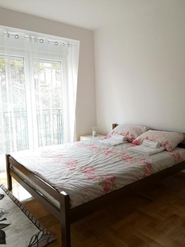 ein Bett in einem Schlafzimmer mit einem großen Fenster in der Unterkunft Apartman Downtown in Vrnjačka Banja