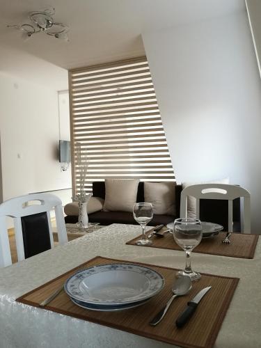 ein Esstisch mit einem Teller und Weingläsern in der Unterkunft Apartman Downtown in Vrnjačka Banja