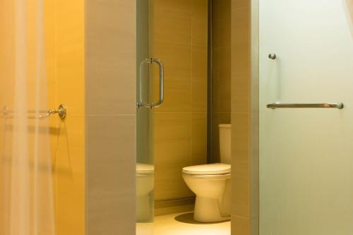 a bathroom with a toilet and a glass shower door at Smell rose beach garden花语海沙滩花园 in Batu Ferringhi