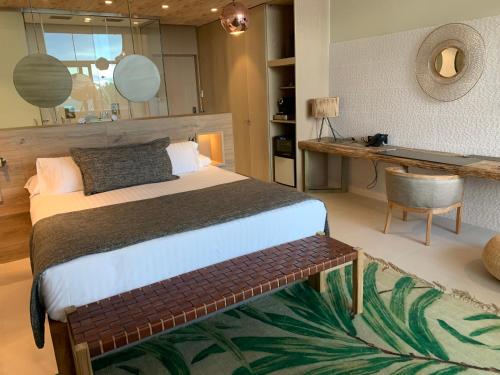a bedroom with a bed and a table and a desk at Playa Grande by Tropical - Adults Only in Gavà