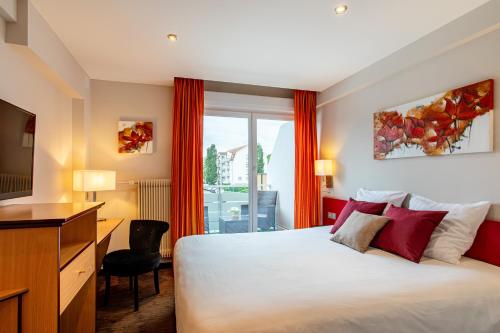 Habitación de hotel con cama, escritorio y ventana en Europe Haguenau – Hotel & Spa en Haguenau