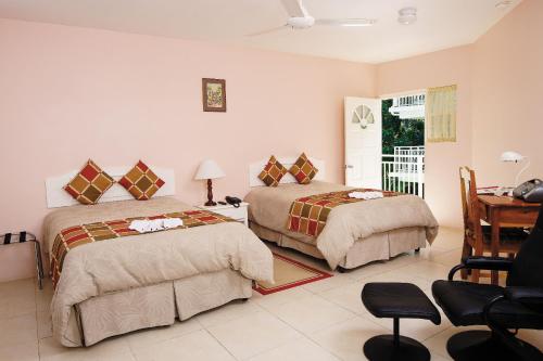 a bedroom with two beds and a table and a desk at Rondel Village in Negril