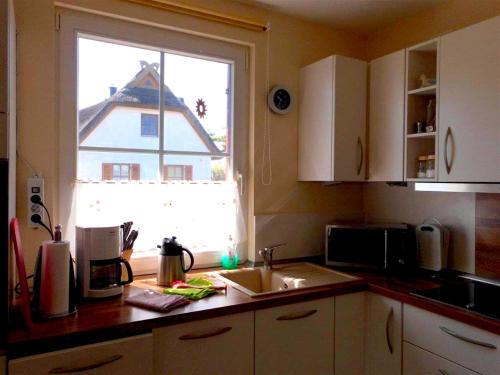 a kitchen counter with a sink and a window at Reetdachhaus Sonnenschein in Mursewiek