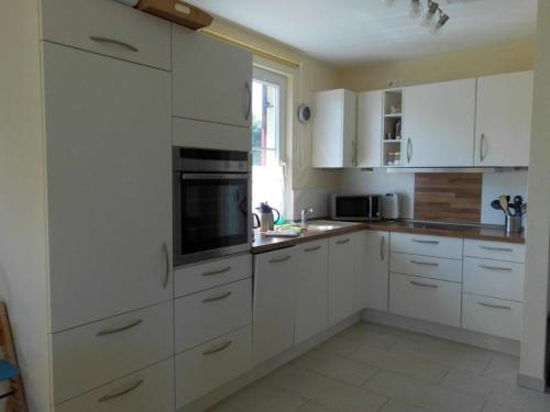 a white kitchen with white cabinets and a window at Reetdachhaus Sonnenschein in Mursewiek