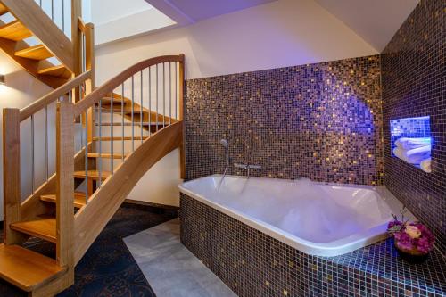 a bathroom with a bath tub and a staircase at Europe Haguenau – Hotel & Spa in Haguenau