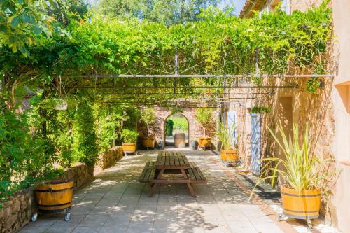 un jardin avec une arche et des plantes en pot dans l'établissement Chateau des Bertrands, au Cannet-des-Maures