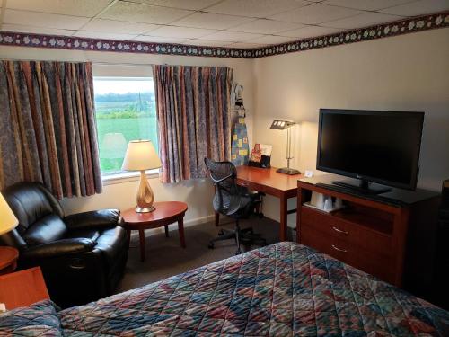 a hotel room with a bed and a desk and a television at Huntingdon Motor Inn in Huntingdon
