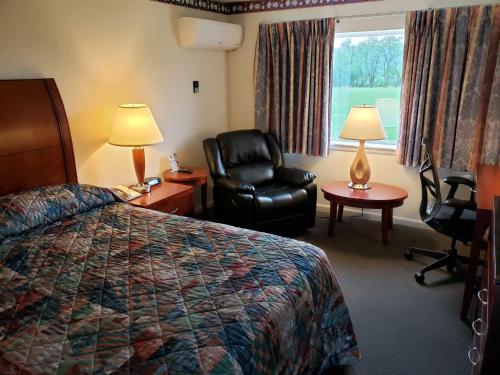 a hotel room with a bed and a chair at Huntingdon Motor Inn in Huntingdon