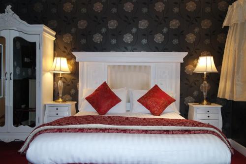 a bedroom with a white bed with red pillows at Gable End Hotel in Great Yarmouth