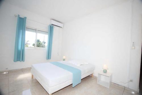 a white bedroom with a bed and a window at Le Frangipanier Villa avec piscine in Saint-Denis