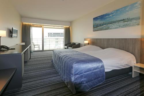 a hotel room with a large bed and a balcony at Vayamundo Oostende in Ostend