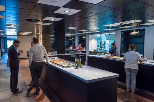a group of people standing at a counter in a restaurant at Postillion Hotel Dordrecht in Dordrecht