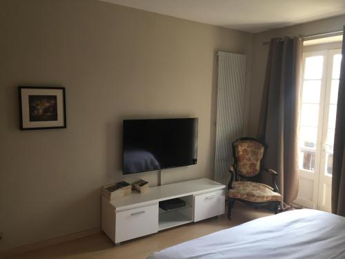 1 dormitorio con TV, silla y cama en Maison en Périgord à 5 mn à pieds du centre Sarlat, en Sarlat-la-Canéda