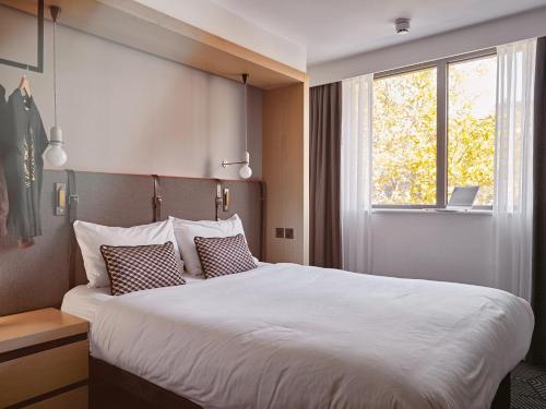 ロンドンにあるAssembly Leicester Squareの大きなベッドと窓が備わるホテルルームです。