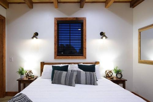 a bedroom with a white bed with pillows and a window at Little Dutch Cabin #3 - 12 min to Magnolia-Baylor in Bellmead