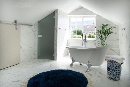 baño blanco con bañera y ventana en Holiday Home Floreat en Orebić