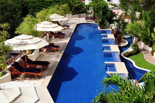 a swimming pool with chairs and umbrellas at a resort at Porto Playa Condo Hotel and Beach Club in Playa del Carmen