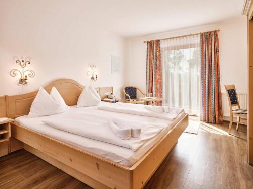 a bedroom with a large bed with white sheets at Hotel Blattlhof in Going am Wilden Kaiser
